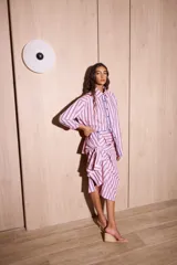 Camisa holgada de popelina de algodón a rayas verticales rosas, grises y azules. Presenta una abertura frontal con ribete festoneado en color azul marino y botones oscuros.