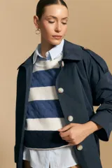 Trench azul marino de corte clásico con cuello amplio, botones frontales grandes en color beige, y detalles en los hombros.