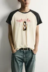 Camiseta regular fit de corte clásico con efecto lavado, cuello redondo negro y mangas cortas ranglán negras. El cuerpo es de color blanco con estampa frontal inspirada en automovilismo con el texto "Asphalt Speed".