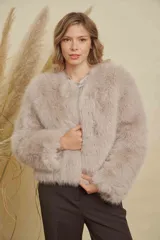 Abrigo corto de piel sintética en tono beige, con cuello redondo y mangas largas. Diseño de corte recto y textura suave.