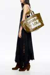 Bolso tipo tote de Bimba y Lola, color dorado con acabado metalizado y efecto arrugado. Presenta un diseño cuadrado con estampado central de la marca en un recuadro oscuro y doble asa de mano en color crema.