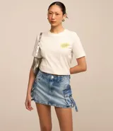Pollera mini de jean con efecto mármol, diseño de tiro medio con bolsillos cargo laterales, lazos decorativos con hebillas y cierre frontal tradicional.