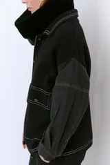 Campera color caramelo con mangas de denim azul oscuro. Presenta cuello alto, cierre frontal con botones, cuatro bolsillos delanteros con solapa y pespuntes blancos decorativos.