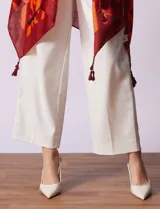 Kimono ligero de poliéster con estampado geométrico en tonos rojo oscuro y naranja. Presenta mangas anchas y terminación con borlas en los ruedos.