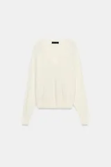 Jersey de punto color blanco crema, con escote en pico, manga larga y sisa ancha terminada en puño.