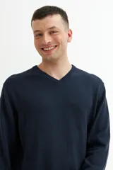 Sweater verde oscuro de tejido de punto, con escote en V y mangas largas.