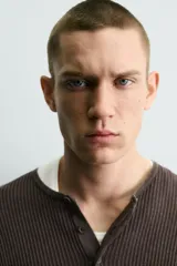 Jersey relaxed fit de punto acanalado color marrón oscuro, con cuello redondo tipo panadera y cierre frontal de tres botones. Tiene manga larga y efecto lavado.