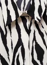 Camisa fluida de manga larga con estampado animal print tipo cebra, cuello camisero y cierre frontal de botones.