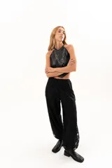 Pantalón de encaje negro con diseño floral, corte holgado y cintura elástica con cordón ajustable. Cuenta con bolsillos laterales.