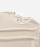 Remera de corte regular confeccionada en tejido texturizado de algodón y poliéster. Presenta cuello redondo y bordes de mangas con detalle de rayas contrastantes en blanco y gris.