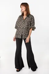 Camisa de lino italiano con estampado a rayas verticales irregulares, de corte holgado, cuello clásico, mangas abullonadas y cierre frontal con botones.