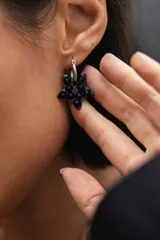 Aro tipo argolla de acero quirúrgico con dije colgante en forma de estrella de color negro, decorado con pequeños cristales brillantes.