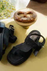 Sandalias de cuero marrón con diseño de punta abierta, tiras ajustables con hebilla metálica y suela de bloque bajo.