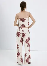 Pantalón de corte regular y tiro medio, con diseño fluido y estampado floral en color bordó sobre fondo beige.