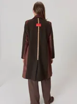 Tapado de lana color marrón oscuro, con diseño de corte recto a la rodilla, solapas clásicas y cierre frontal con botones. Presenta detalles en contraste en los hombros y laterales.