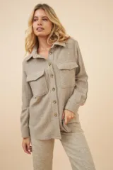 Camisa estilo leñador color beige con textura en espiga, de manga larga, con cuello clásico, cierre frontal con botones, dos bolsillos de parche con solapa abotonada en el pecho y puños abotonados. Confeccionada en lana fina sin teñir.