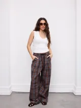 Pantalón de corte ancho y relajado, con estampa a cuadros en tonos marrones y azules. Cuenta con cintura elástica con cordón de ajuste y bolsillos laterales.