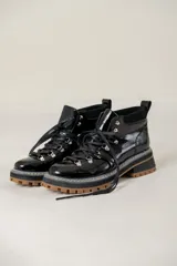 Borcego de cuero de estilo montañés con cordones, ganchos metálicos, suela track dentada en color suela y detalle de estrella lateral.
