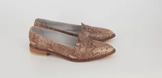 Mocasines de cuero plateado con acabado texturado, diseño clásico con costuras visibles y vira de suela natural cosida. Cuenta con taco plano de 2 cm y plantilla anatómica.