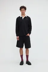 Remera polo de manga larga en color negro, confeccionada en algodón pesado con textura suave. Cuenta con cuello camisero en contraste de color blanco, media cartera con botones y bordado sutil de la marca en el pecho. Presenta un calce relaxed.