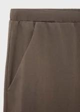 Pantalón de tiro medio color marrón, con diseño recto y holgado, cintura elástica con cordón ajustable y bolsillos laterales.