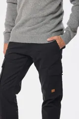 Pantalón cargo azul marino con bolsillos laterales con solapa y cinturón de cuero marrón.