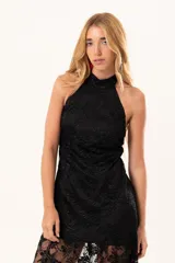 Vestido largo de encaje negro con cuello halter, compuesto por un minivestido base y una sobrefalda transparente de encaje con diseño floral.
