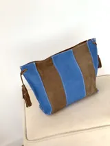 Cartera tipo sobre de cuero con diseño de rayas verticales en tonos verde menta y marrón tostado. Cuenta con detalles de borlas colgantes en los laterales.