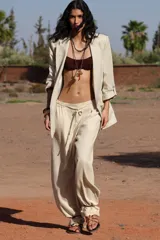 Blazer color beige confeccionada en lino, de corte recto, con cuello solapa, hombreras y mangas 3/4 con trabilla y botón dorado.