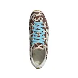 Championes Adidas modelo Japan con exterior de pelo sintético con estampado animal print tipo vaca en tonos marrón y blanco, tres tiras laterales y refuerzo en el talón de cuero blanco, cordones celestes y suela de goma color tostado.