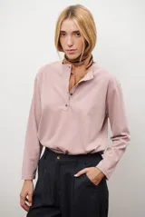 Remera de manga larga en color rosado, con cuello redondo y cierre frontal parcial con botones. Presenta un diseño de corte recto y estilo minimalista.