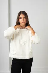 Buzo de punto color blanco, de corte holgado y cuello redondo, con diseño de flores aplicadas con detalles de mostacillas bordadas.
