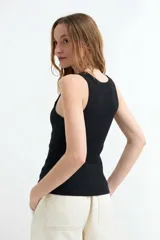 Top tejido de punto color blanco, sin mangas, con escote geométrico y corte al cuerpo.