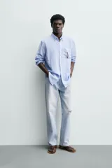 Camisa regular fit de manga larga con diseño a rayas verticales celestes y blancas. Cuenta con cuello abotonado, bolsillo de parche en el pecho y cierre frontal con botones.