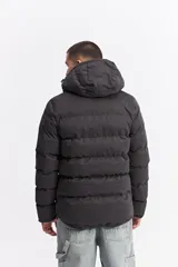 Campera puffer con capucha, diseño acolchado, cierre frontal y bolsillos laterales. Presenta un interior en contraste de color verde oliva.