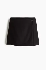 Short pollera mini de diseño cruzado, color negro, con cierre frontal mediante un botón y cierre oculto lateral.