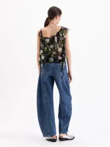 Jeans de tiro medio con silueta slouchy y corte amplio. Presenta recortes verticales que estructuran la prenda, generando volumen desde el muslo hasta la bota. Confeccionado en denim de lavado clásico con desgastes localizados.