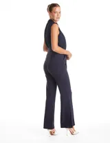 Enterito de crepe color azul marino, con torso plisado sin mangas y cuello alto. Presenta corte en la cintura con lazo de ajuste y pantalón de pierna recta con bolsillos funcionales.