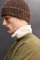 Sudadera de ajuste regular, color verde oliva, con cuello redondo y manga larga. Presenta una textura irregular en el tejido, similar al borreguito o bouclé.