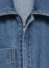 Mono largo de denim azul con cuello camisero, mangas cortas, cierre frontal con cremallera oculta, cinturón ajustable con hebilla metálica, bolsillos laterales y un bolsillo de parche en el pecho.