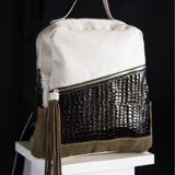 Mochila de cuero vacuno color blanco, negro y verde, con bolsillo frontal con cierre, bolsillos laterales, interior forrado con bolsillo con cierre y bolsillo para celular.