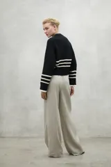 Sweater color crema con rayas horizontales negras en el pecho y los puños, de corte holgado y cuello redondo.