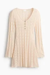 Vestido mini de punto de viscosa estilo crochet, con escote en V y botones frontales. Cuenta con mangas largas y ribetes festoneados en los puños y el bajo.