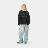 Buzo negro de corte oversize con cuello redondo, mangas largas con costuras laterales blancas y bordes desflecados.