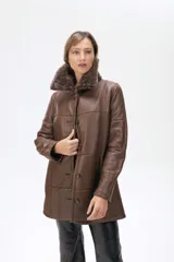 Campera de cuero marrón con cuello de piel sintética, cierre frontal con botones y diseño de paneles. Presenta un largo a la cadera y mangas largas.