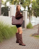 Botas de caña alta confeccionadas en cuero color marrón caoba. Presentan un diseño robusto con tres hebillas metálicas ajustables en el lateral superior y una correa con hebilla y remaches metálicos en la zona del tobillo. Cuentan con un taco bajo cuadrado y suela de goma resistente.