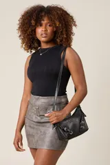 Bandolera color crema con correa fina regulable, cierre superior y herrajes metálicos plateados con forma de hebilla.