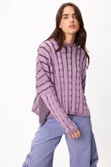 Sweater de punto con diseño de trenzas verticales y rayas horizontales en las mangas, cuello redondo y corte holgado.