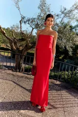 Vestido largo rojo de fiesta con escote palabra de honor y capa superpuesta en el pecho, de corte recto y ajustado.