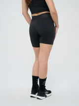 Biker deportiva Umbro para mujer, de color negro, confeccionada con tejido elástico y pretina cruzada con elástico personalizado de la marca.
